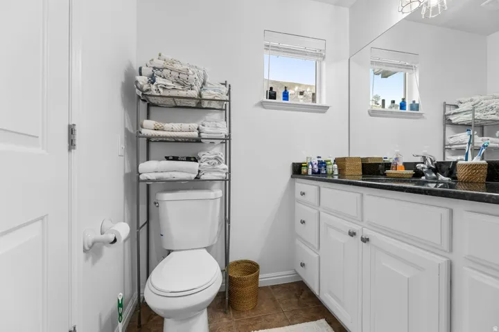 Bathroom vanity featuring a dark countertop, dual under-mount sinks, and white cabinetry with brushed nickel hardware