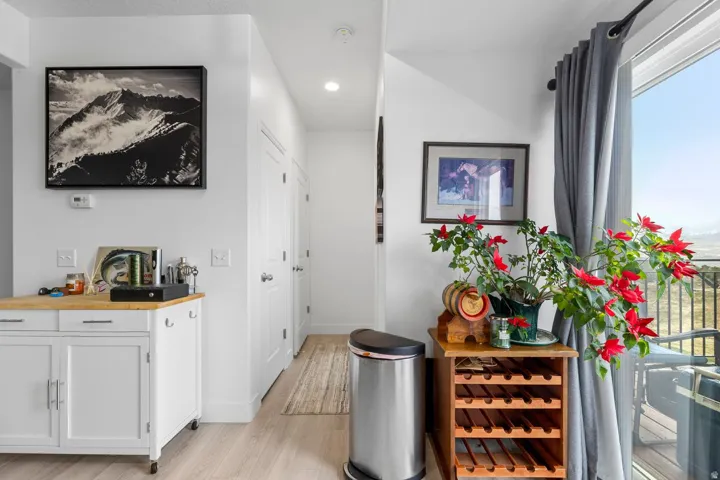 Light wood-finish flooring extending from the living area into a hallway with multiple white panel doors