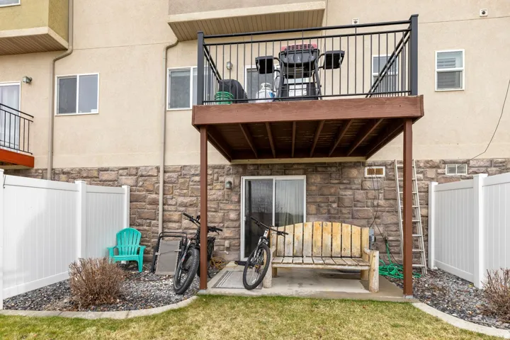 Exterior featuring a second-story wood-finish deck with black metal railing, a sliding glass door, and a stone-finish foundation