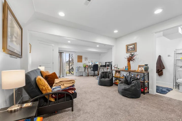 Recessed lighting illuminates this carpeted lower-level space, featuring a sliding glass door for exterior access