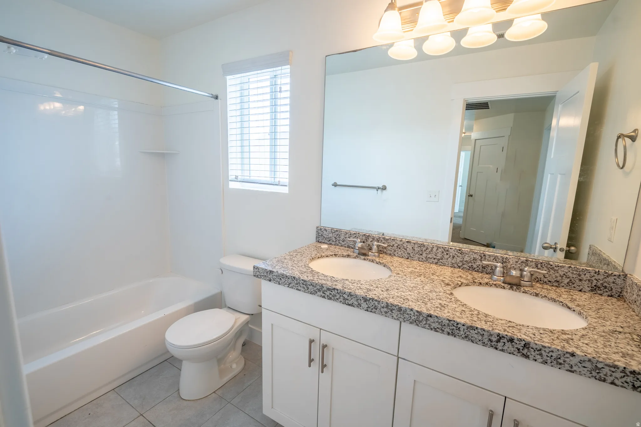 Double vanity with a speckled countertop and undermount sinks, featuring a large wall-mounted mirror