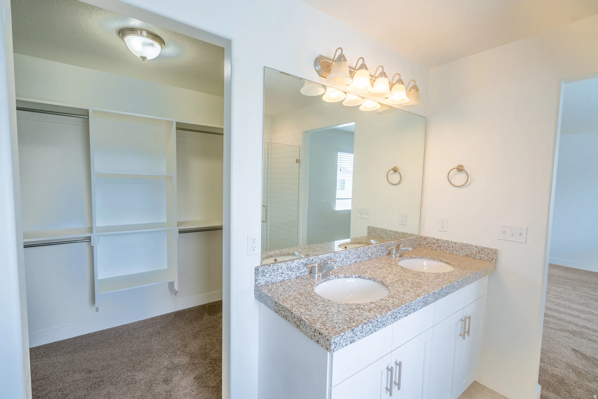 Double vanity with granite-style countertop, dual undermount sinks, and ample storage cabinetry