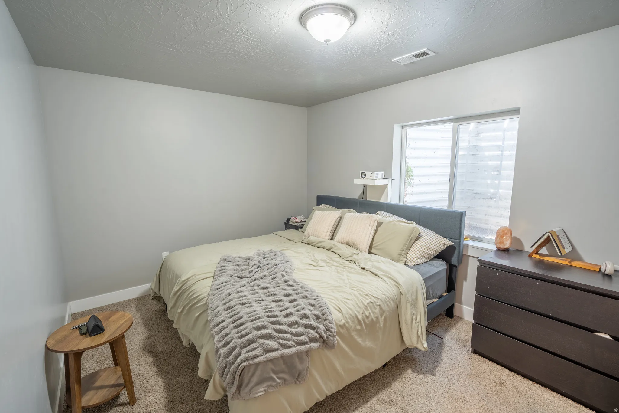 Bedroom featuring light gray walls, textured ceiling, a flush-mount ceiling light fixture, and a single window