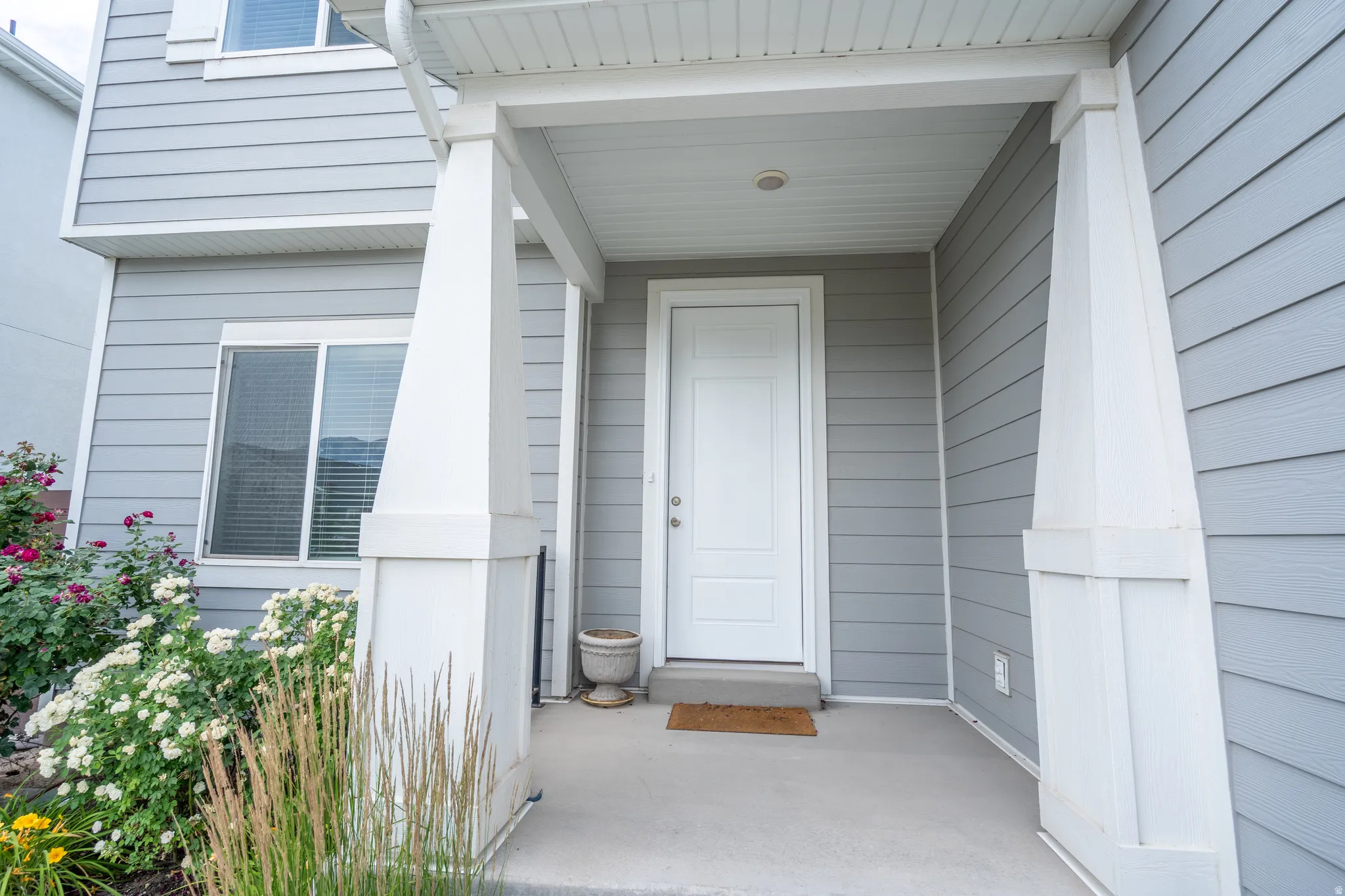 Inviting covered entry with substantial white columns and a solid white door