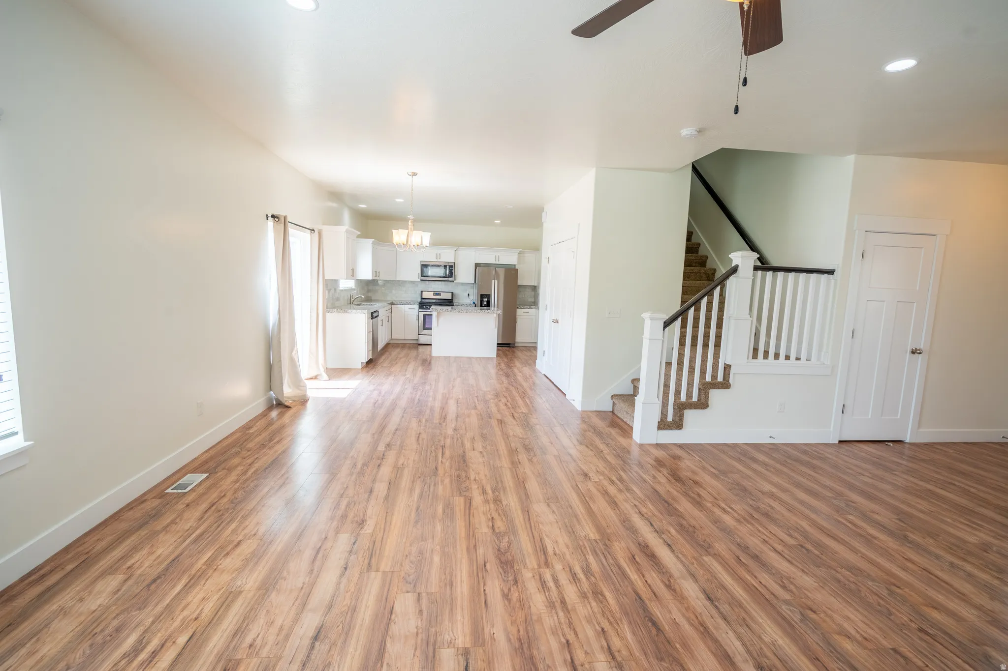 Open-concept living space featuring wood-finish flooring, recessed lighting, and a neutral color palette