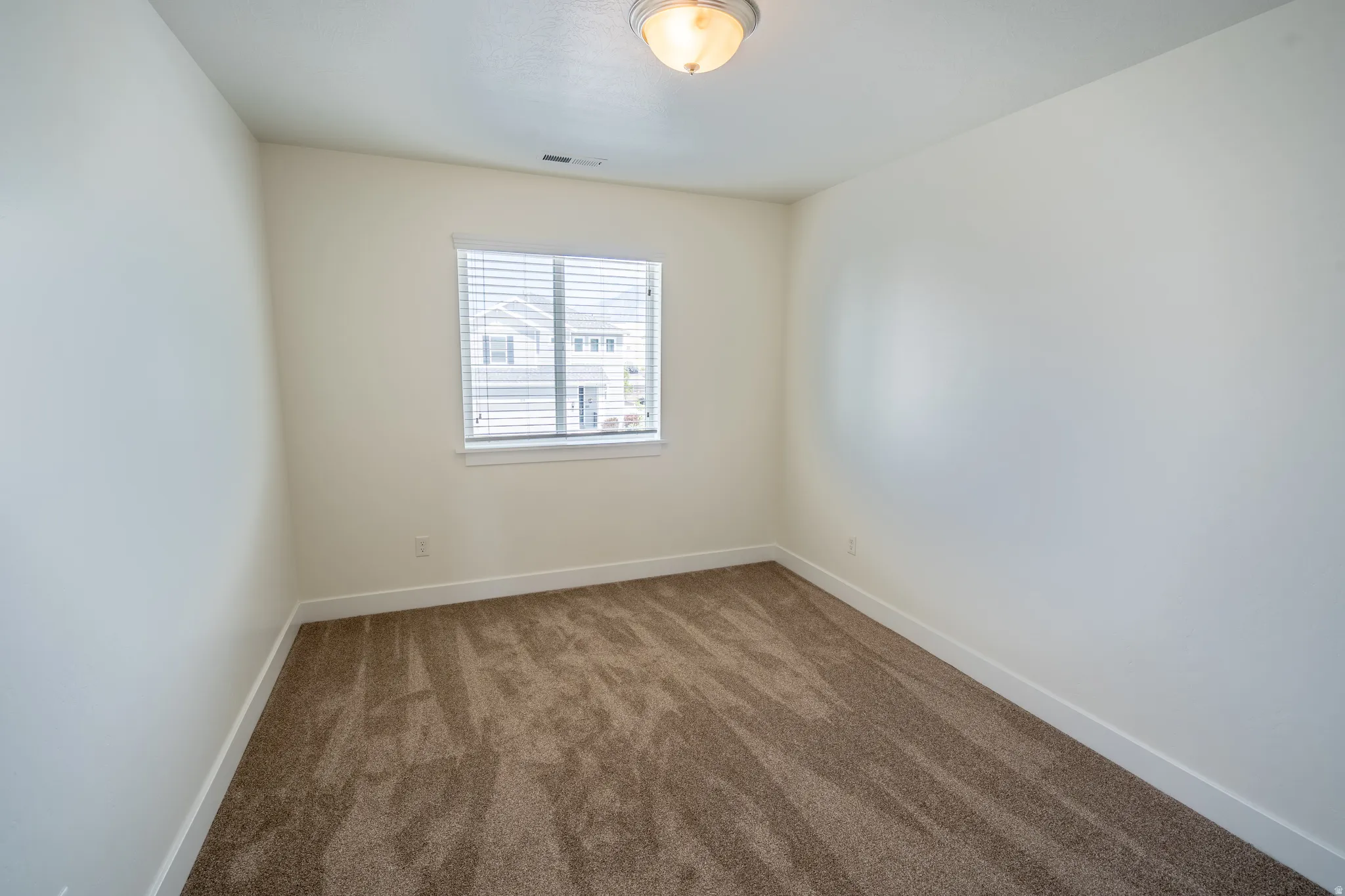 Room featuring neutral carpeting, white walls, and a window with horizontal blinds