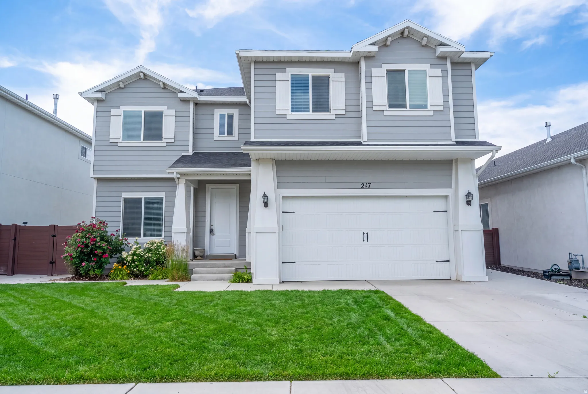 Two-story residence featuring light gray siding, white trim, and a two-car garage with carriage-style hardware