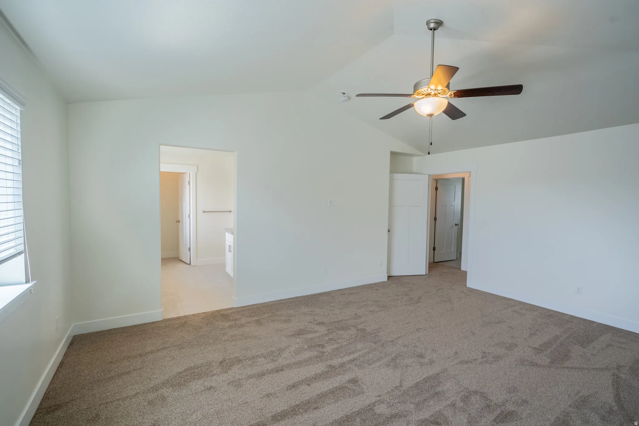 Carpeted interior space with a vaulted ceiling and a ceiling fan