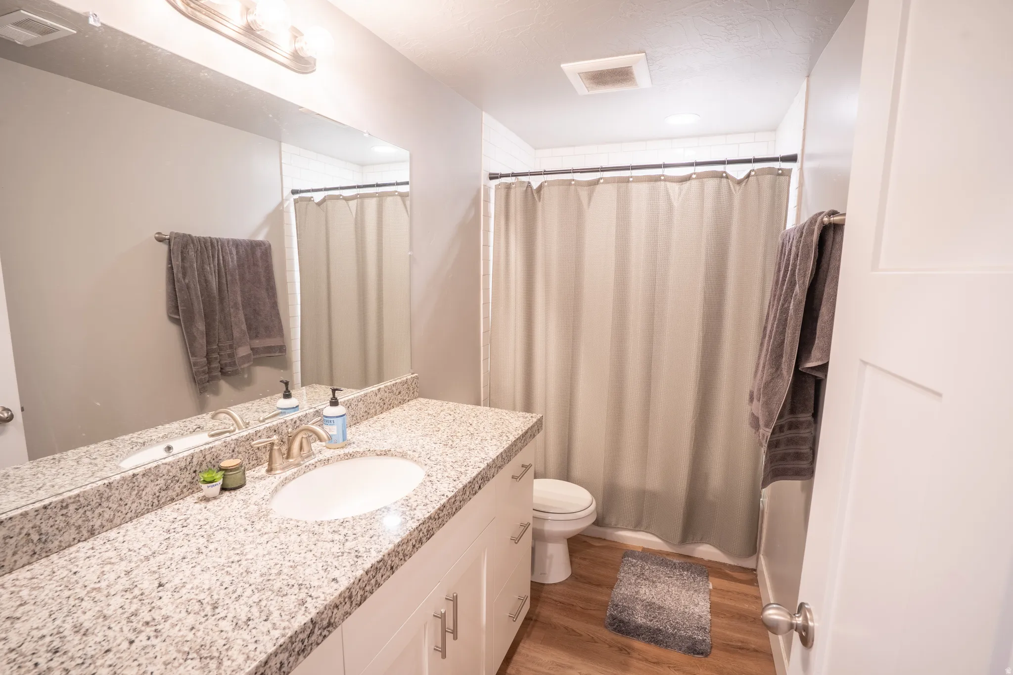 Bathroom featuring a granite countertop vanity with an undermount sink, brushed nickel faucet, and white cabinetry