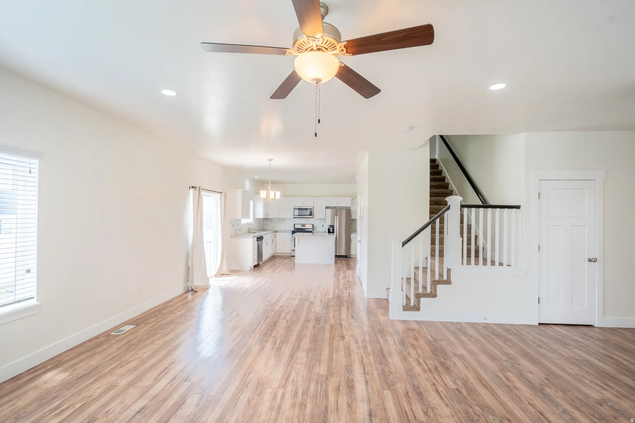 Expansive open-concept living area featuring wood-finish flooring, recessed lighting, and a ceiling fan