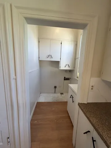 Utility room with built-in cabinetry, wood-finish flooring, and a white countertop