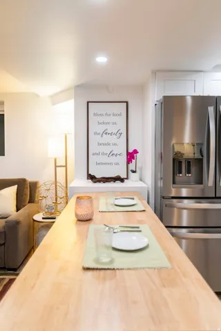 Spacious kitchen area featuring a light wood-finish countertop, stainless steel refrigerator, white cabinetry, and recessed lighting