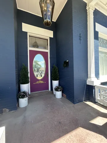 Entryway featuring a purple door with an oval window, coordinating transom window, and a dark blue brick exterior