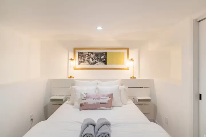 Bedroom featuring a built-in headboard with integrated side tables, recessed ceiling lighting, and wall-mounted sconces