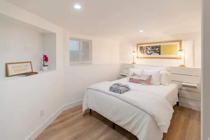 Bedroom featuring wood-finish flooring, recessed lighting, and a built-in headboard with integrated shelving and wall sconces