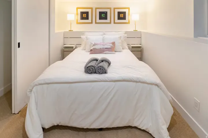 Carpeted bedroom featuring a built-in recessed headboard alcove, two integrated bedside tables, and a sliding door
