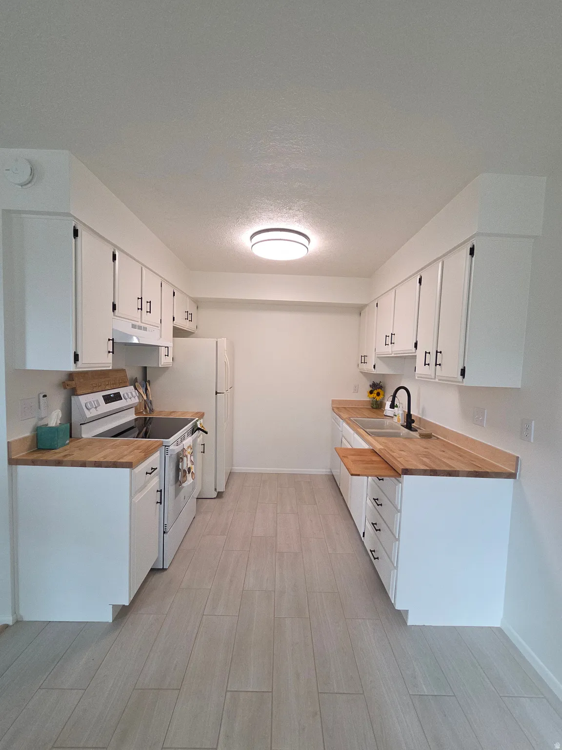 Updated kitchen with new range, range hood, dishwasher, butcher block countertops, faucet and tile flooring.