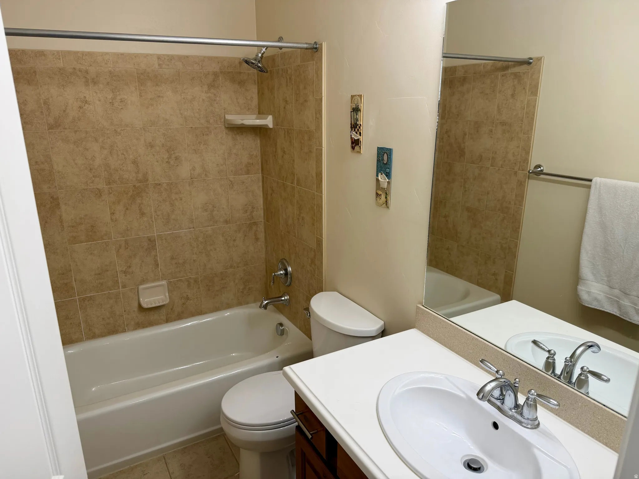 Bathroom featuring a white bathtub, ceramic tile surround, a single vanity with an integrated sink, a large wall mirror, and a toilet