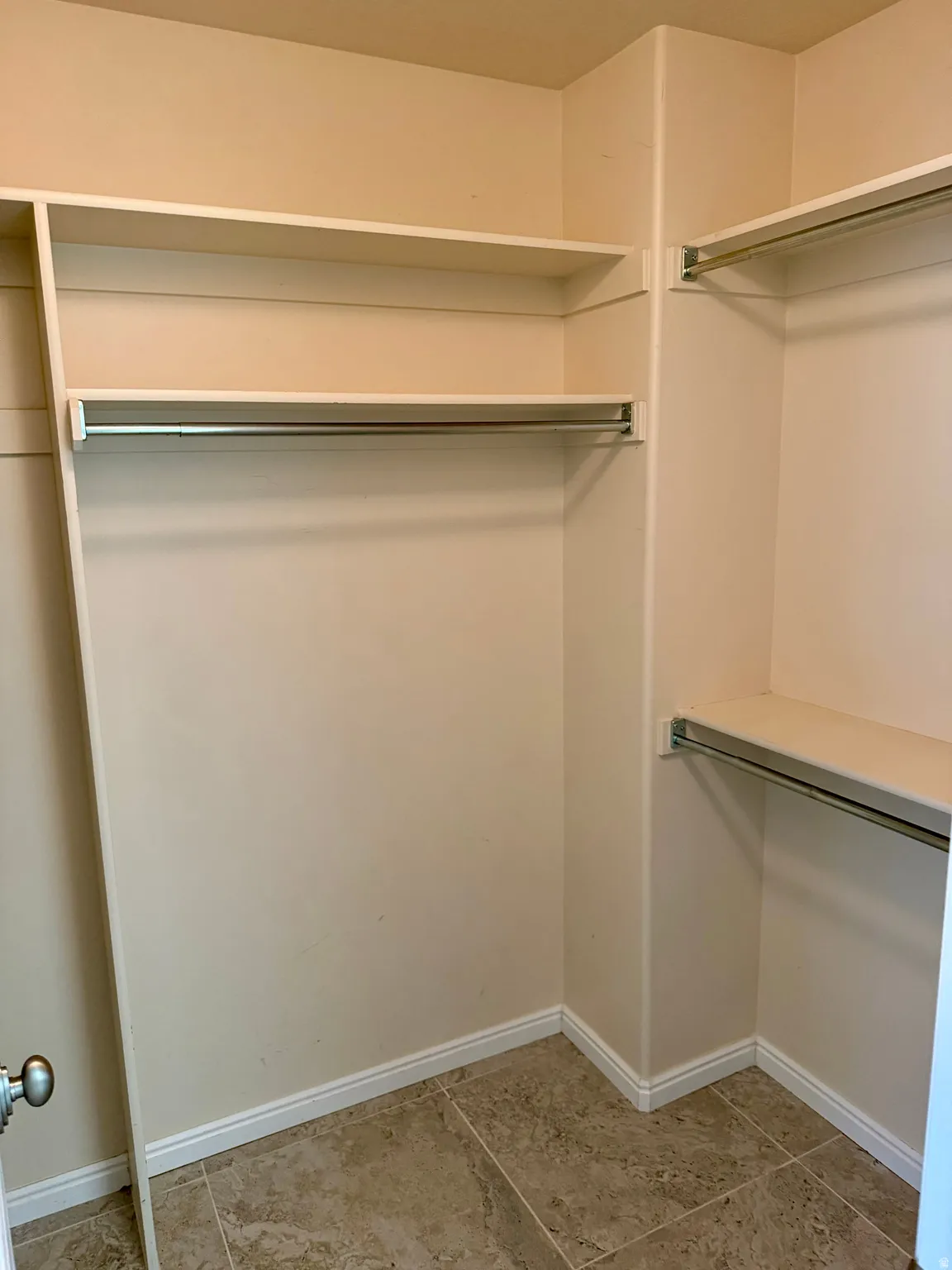 Walk-in closet featuring built-in shelving, chrome hanging rods, tiled flooring, and baseboard trim