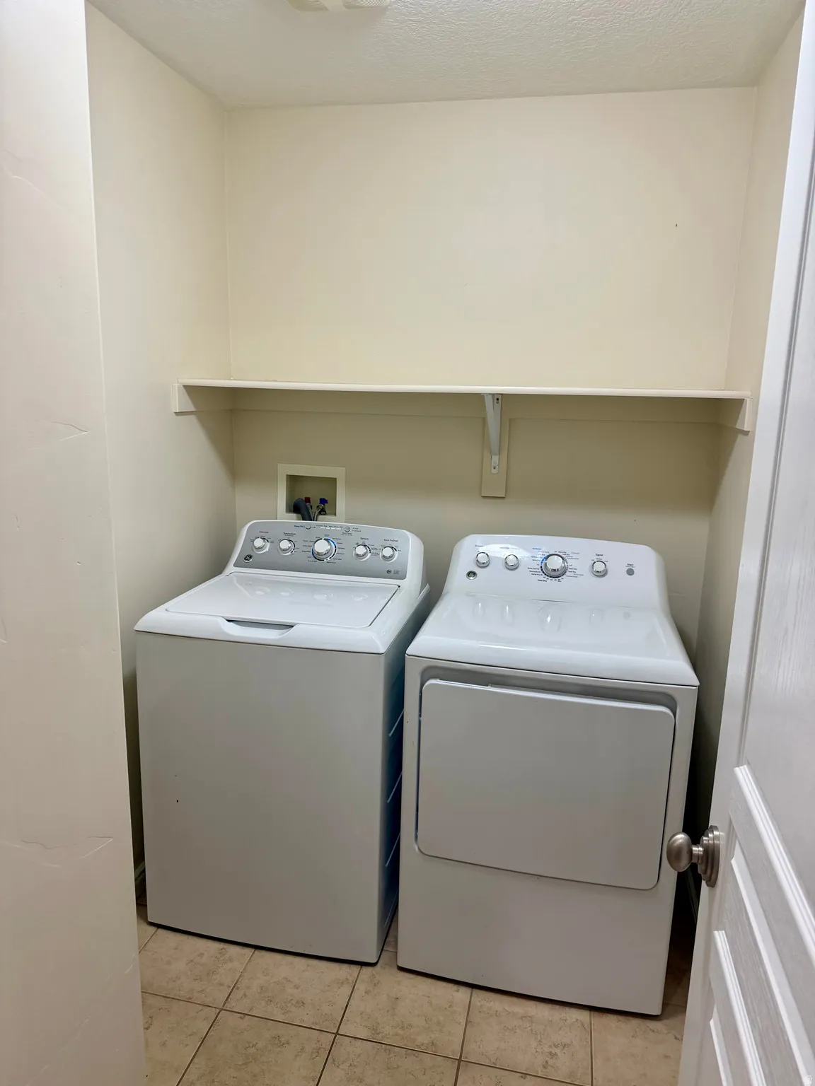 Dedicated laundry area featuring a built-in white shelf and neutral-toned wall paint