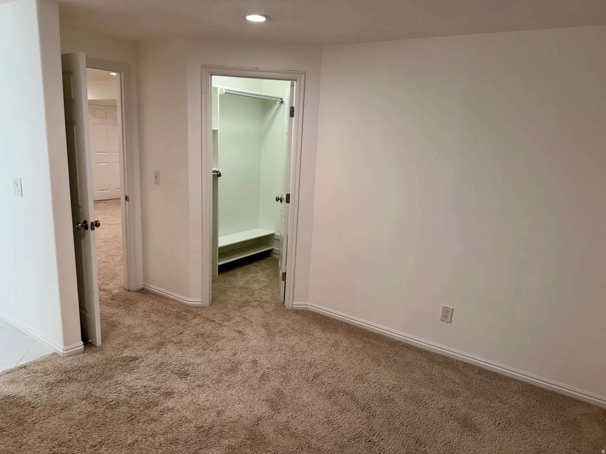 Carpeted interior space with a recessed light fixture and a closet featuring a built-in shelf and hanging rod