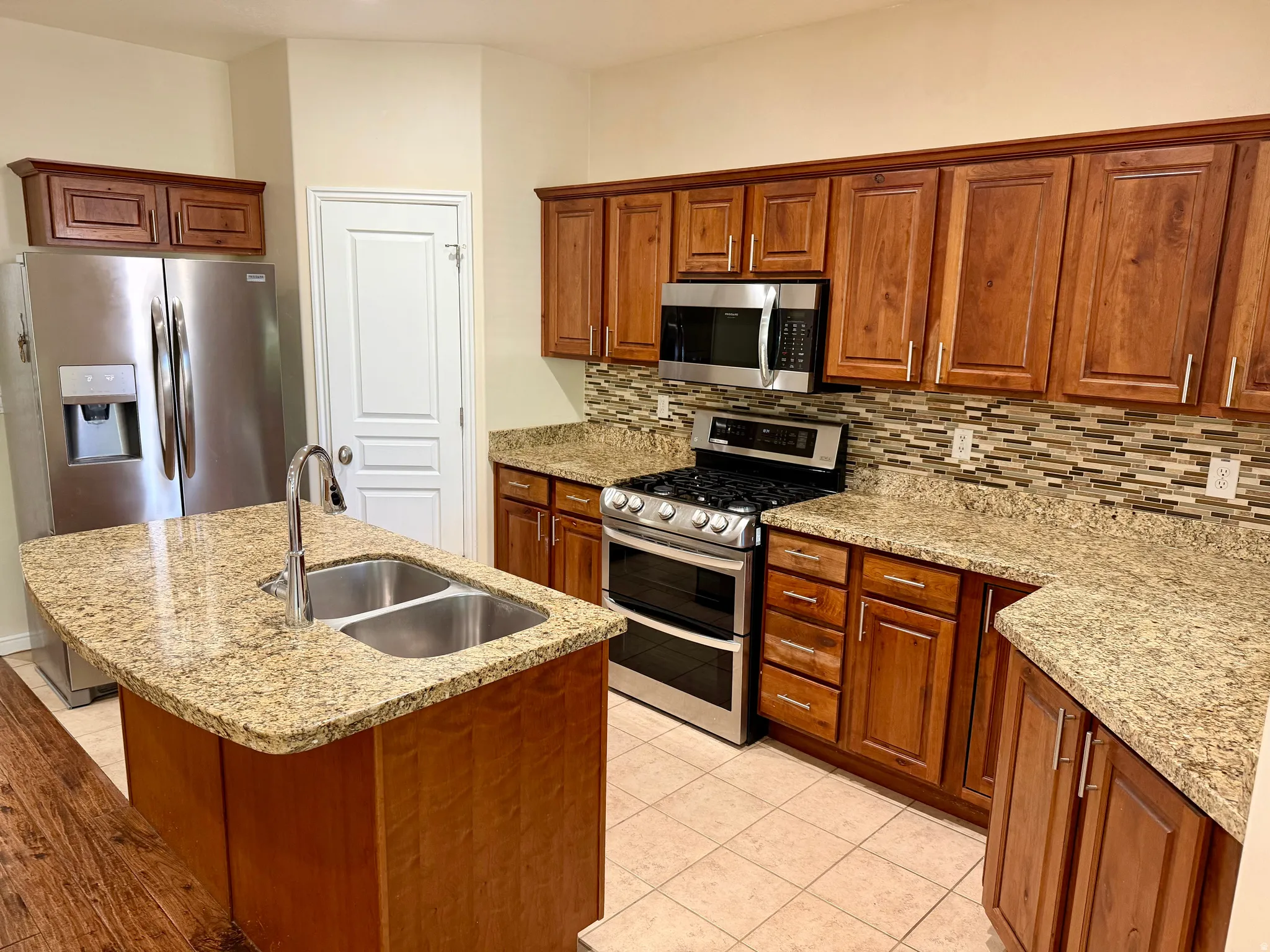 Kitchen featuring wood-finish cabinetry, granite-style countertops, and a mosaic tile backsplash