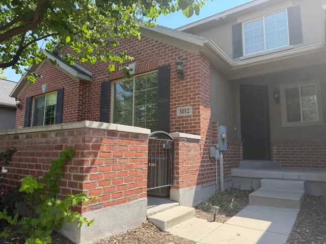 Brick and stucco exterior featuring multiple windows with dark shutters