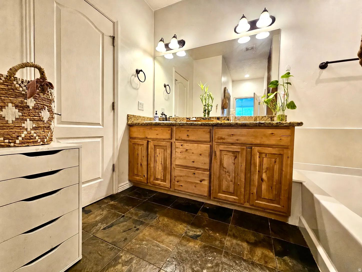 Bathroom featuring a double vanity with wood cabinetry and a stone countertop
