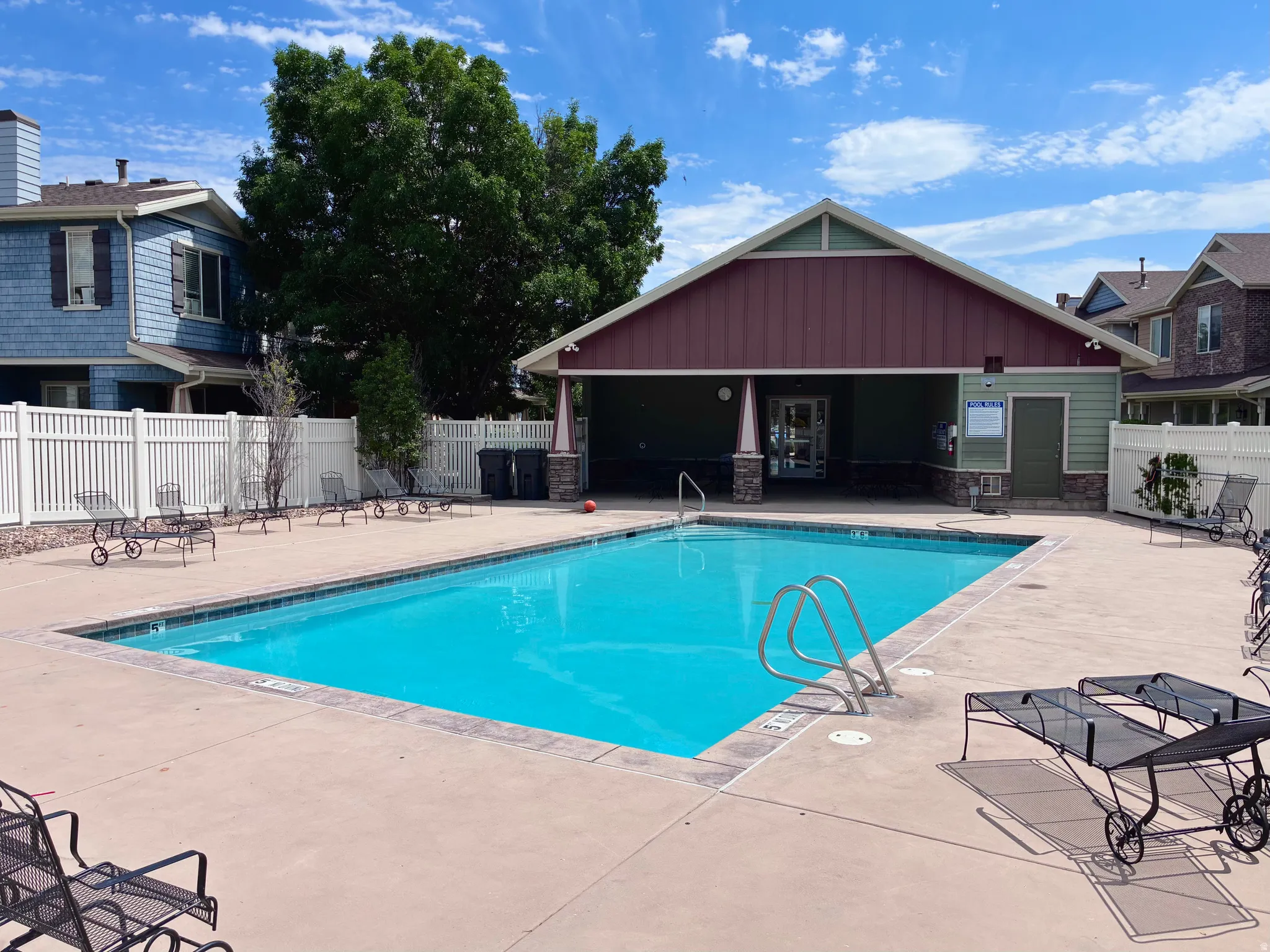 Outdoor swimming pool with concrete decking and adjacent pool house featuring a covered patio