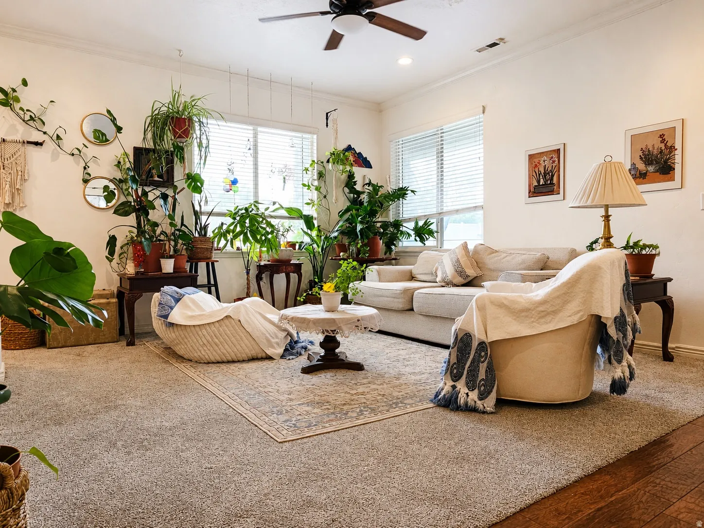 Spacious living area featuring light-colored walls, a ceiling fan with integrated lighting, and multiple windows with blinds