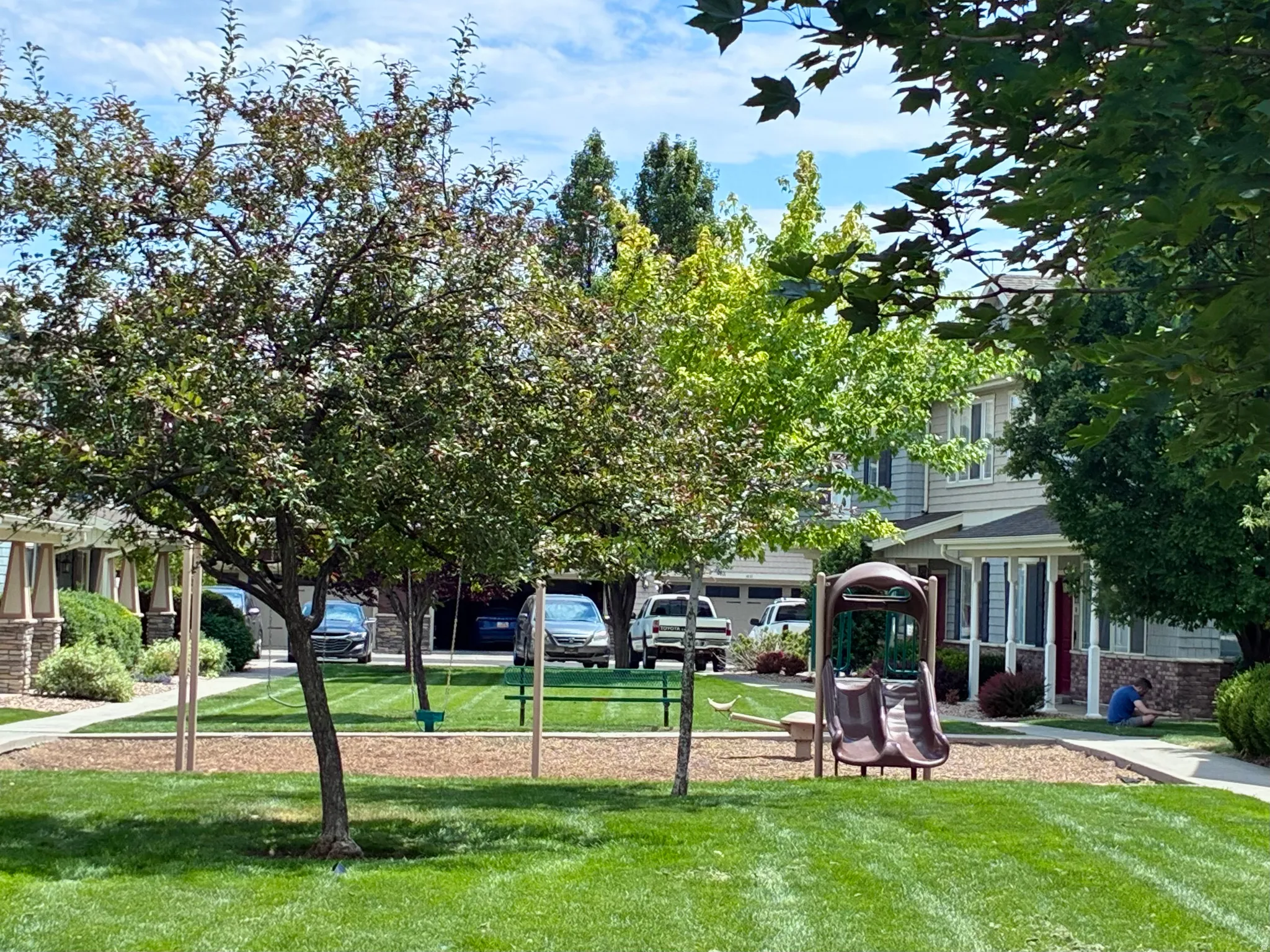 Community green space featuring a playground with a slide and swings