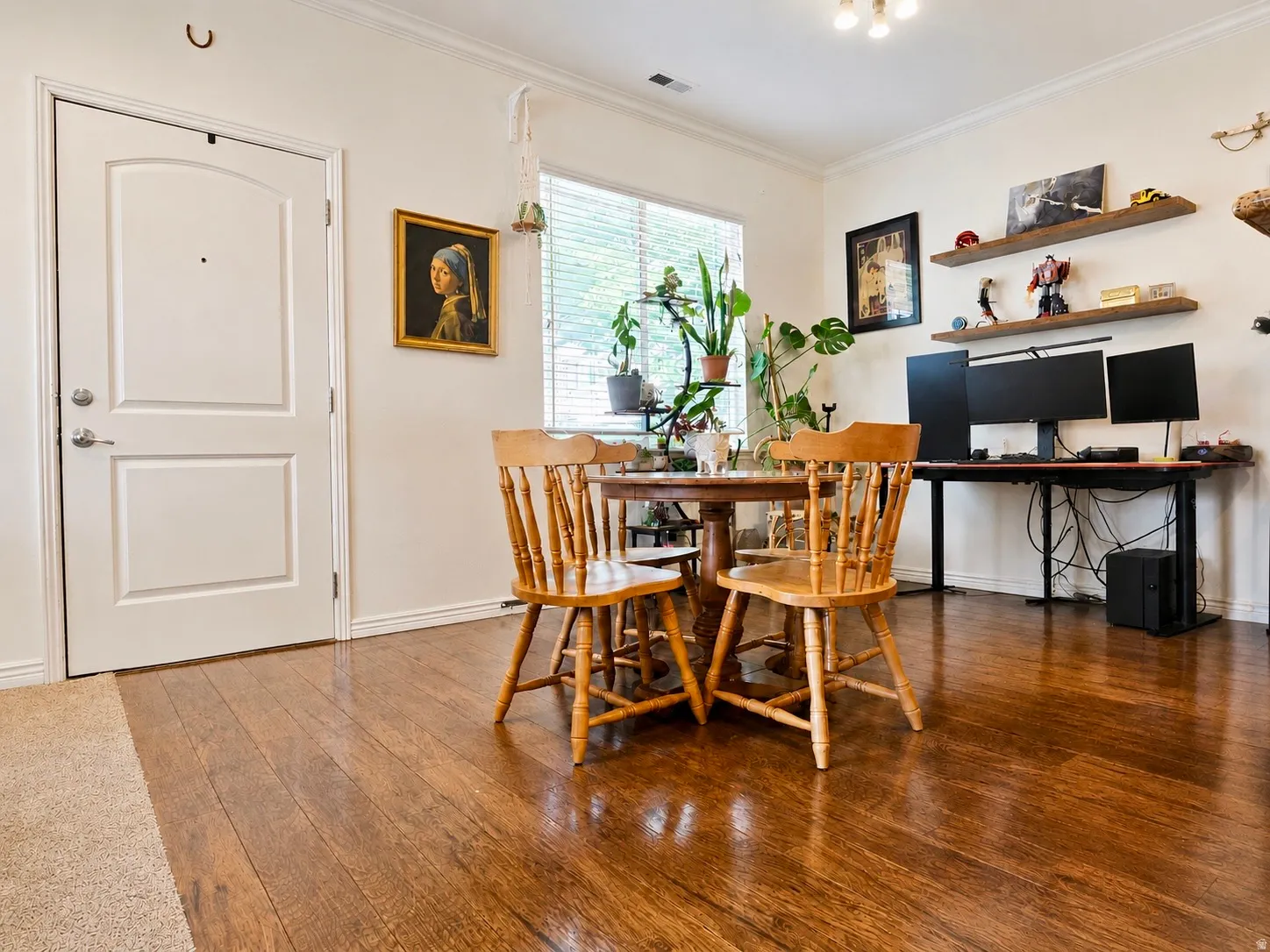 Hardwood-style flooring extending through the living area, complemented by white baseboards and crown molding