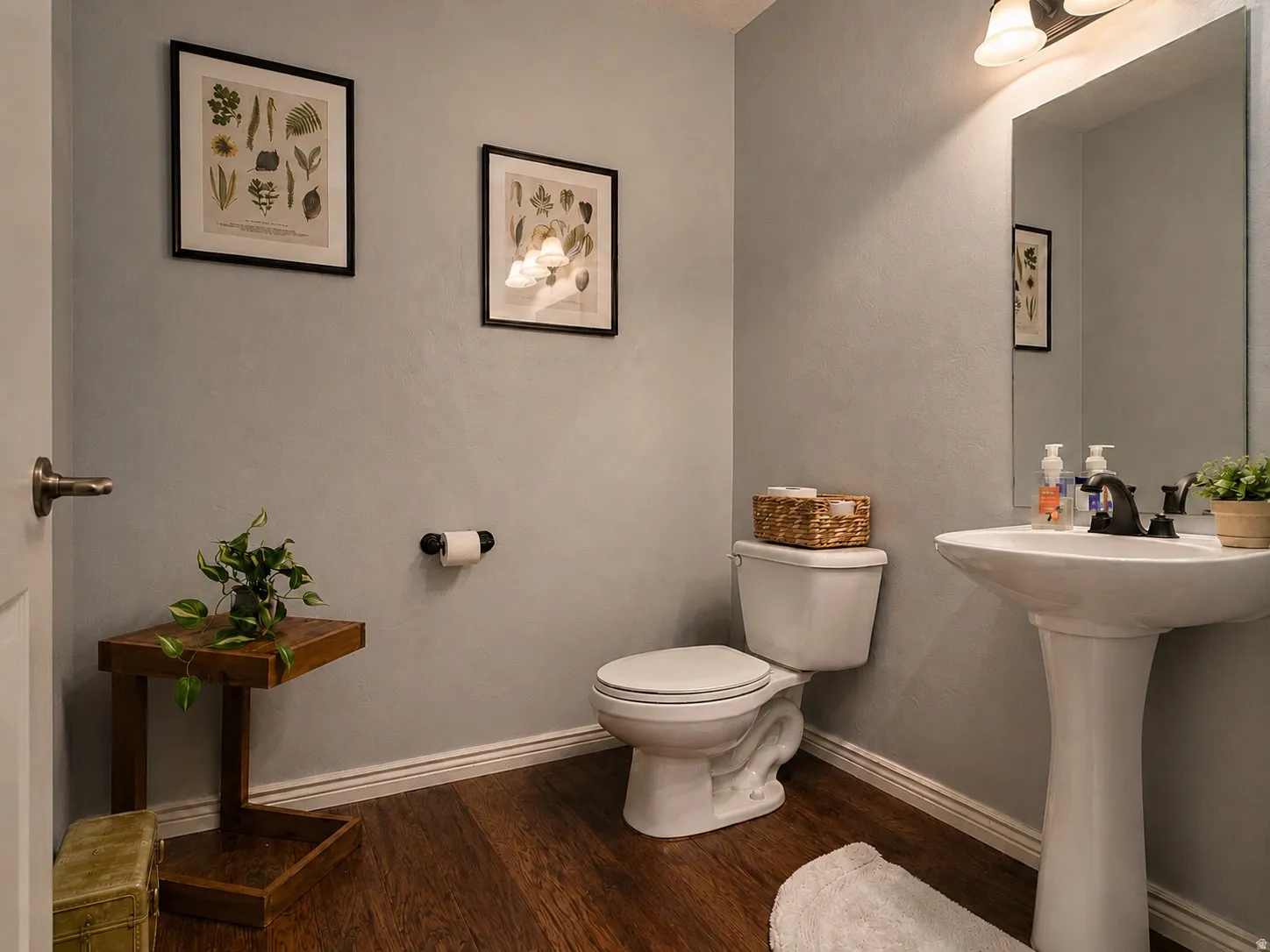 Powder room featuring wood-finish flooring, a white pedestal sink, and a white toilet