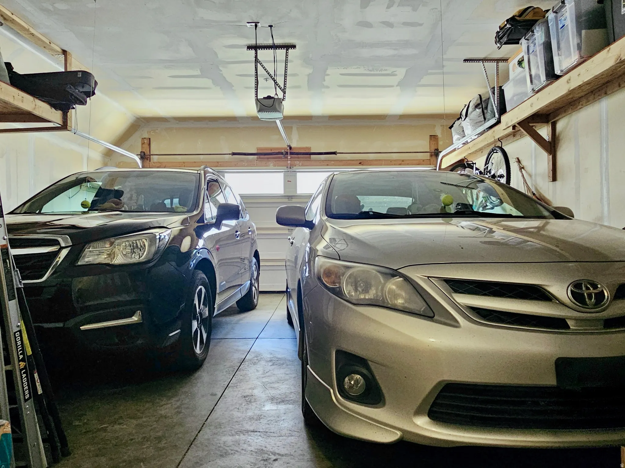 Two-car garage with a concrete floor, automatic garage door opener, and natural wood shelving