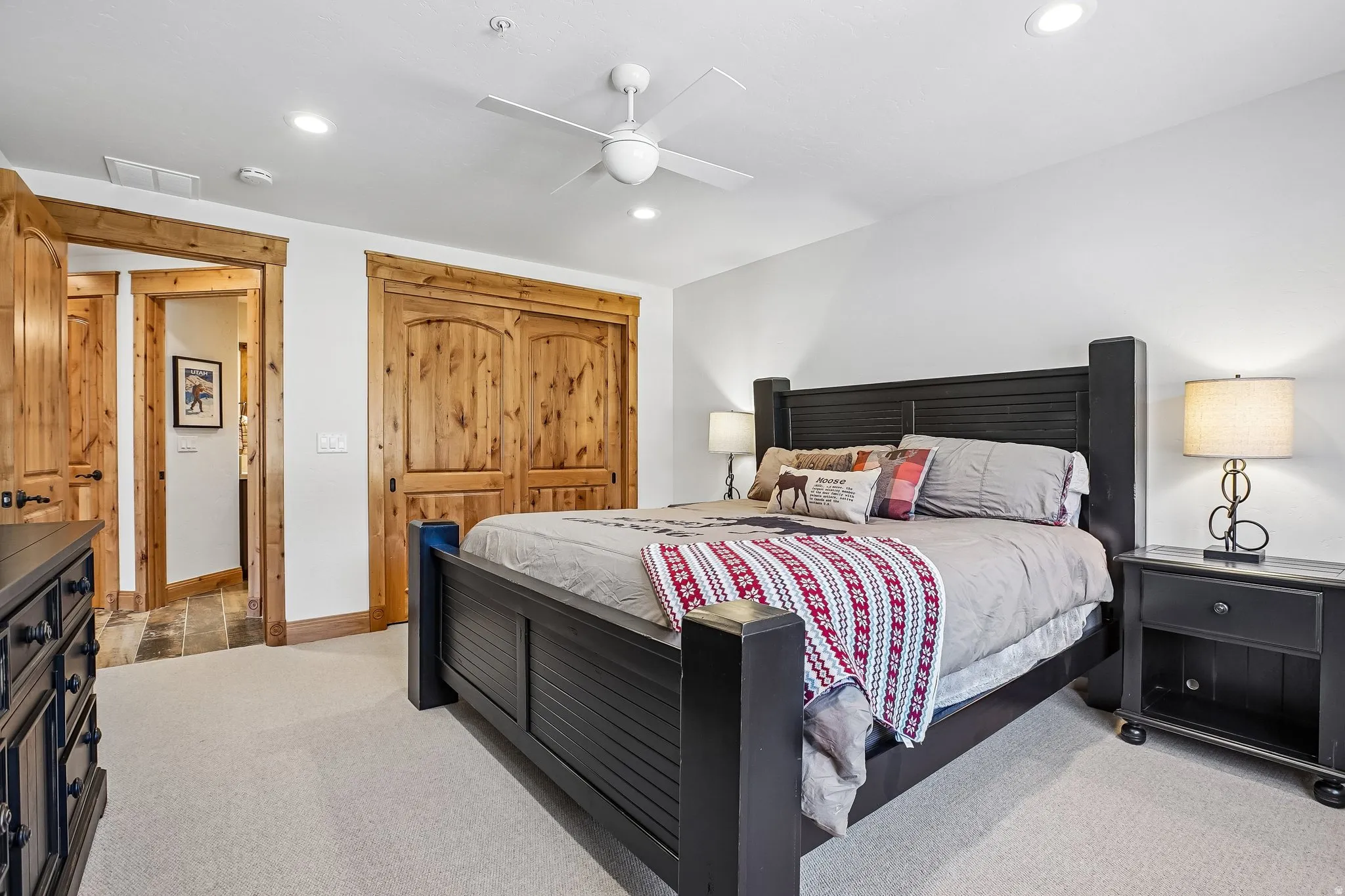 Carpeted bedroom featuring natural wood doorframes and solid wood closet doors