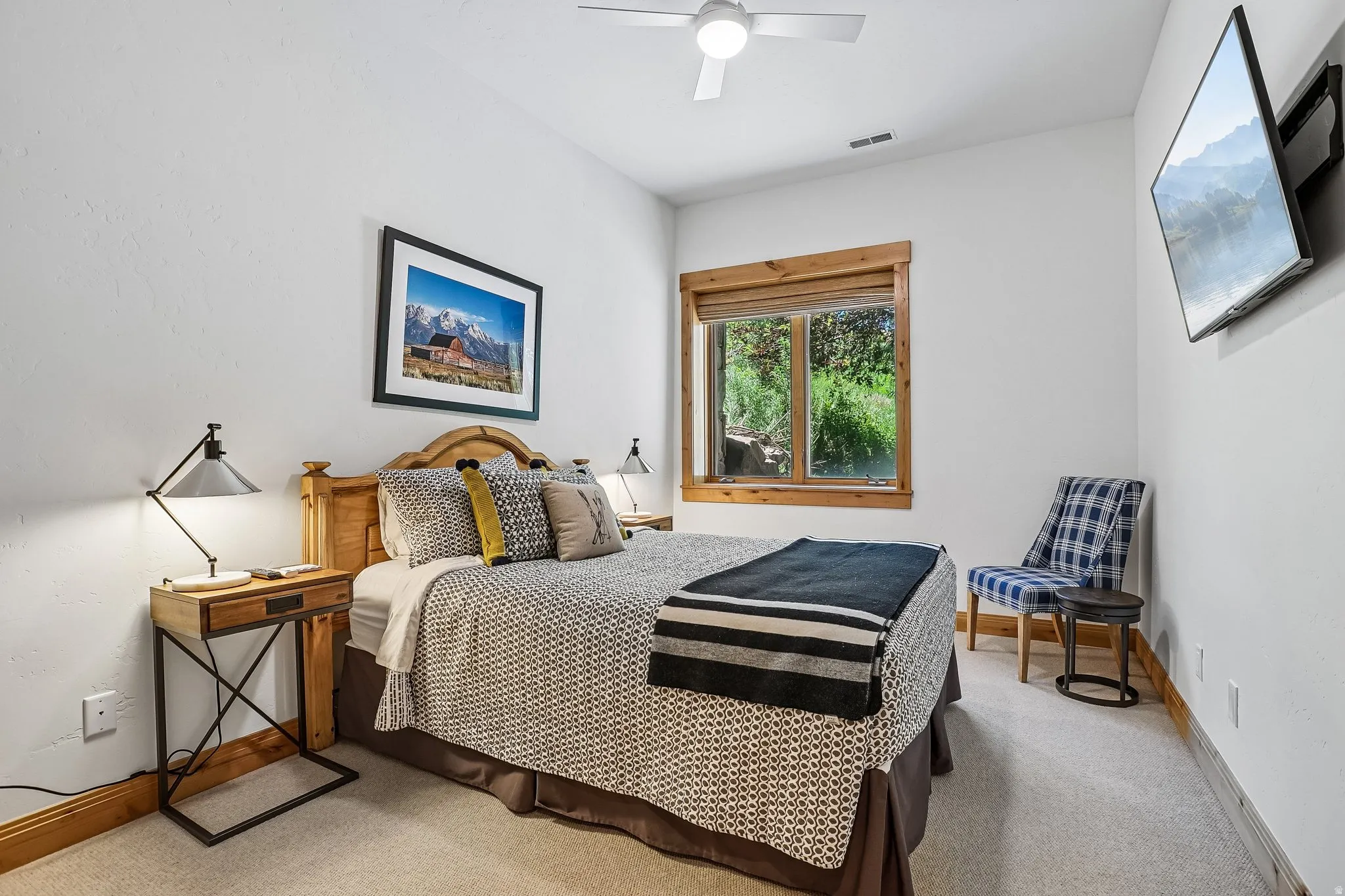 Carpeted room with a ceiling fan, a window with wood trim, and a wall-mounted television