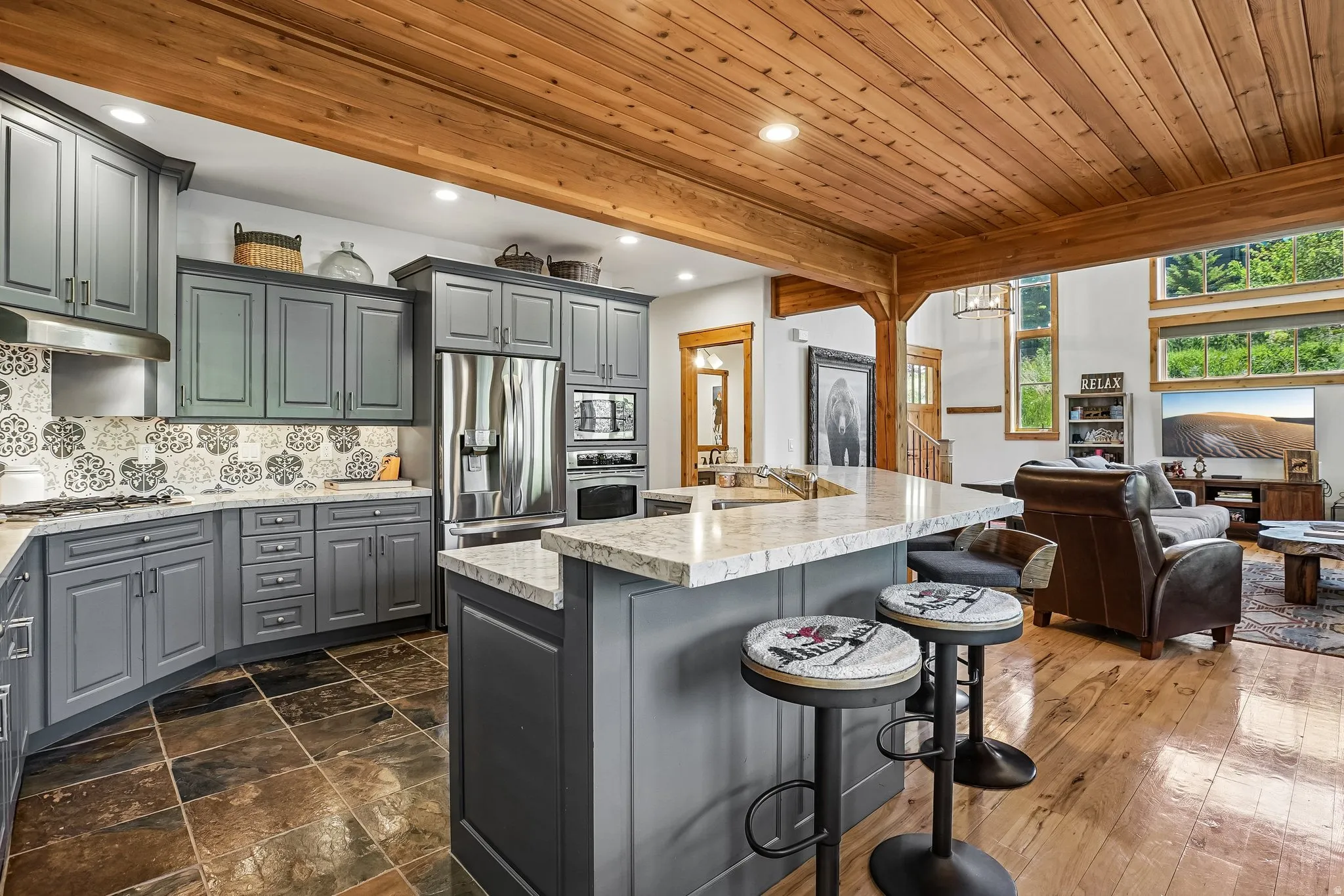Kitchen featuring granite countertops, stainless steel appliances, grey cabinetry, and a patterned tile backsplash