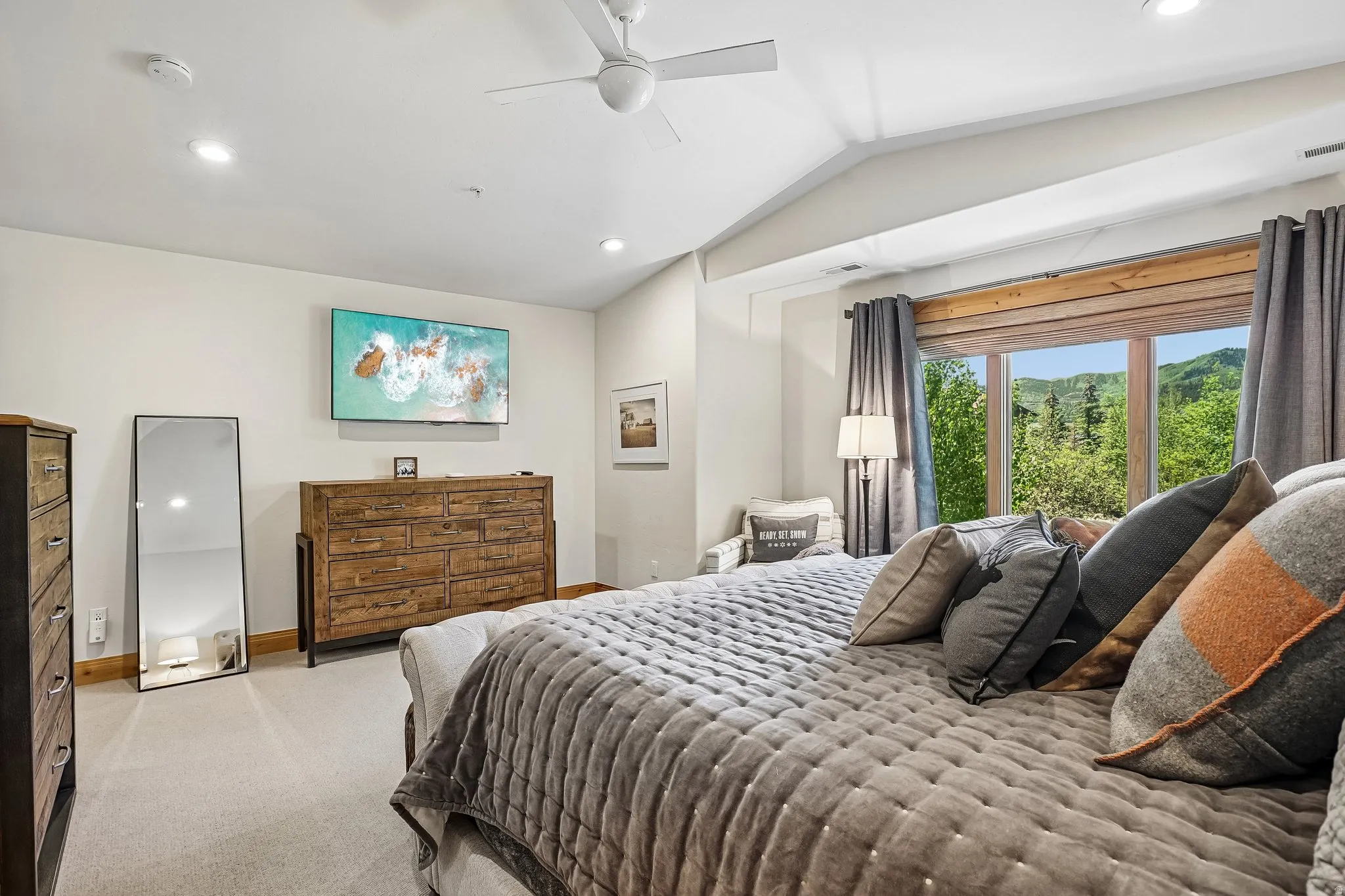 Spacious bedroom featuring vaulted ceilings, recessed lighting, a ceiling fan, and large windows with integrated wood trim