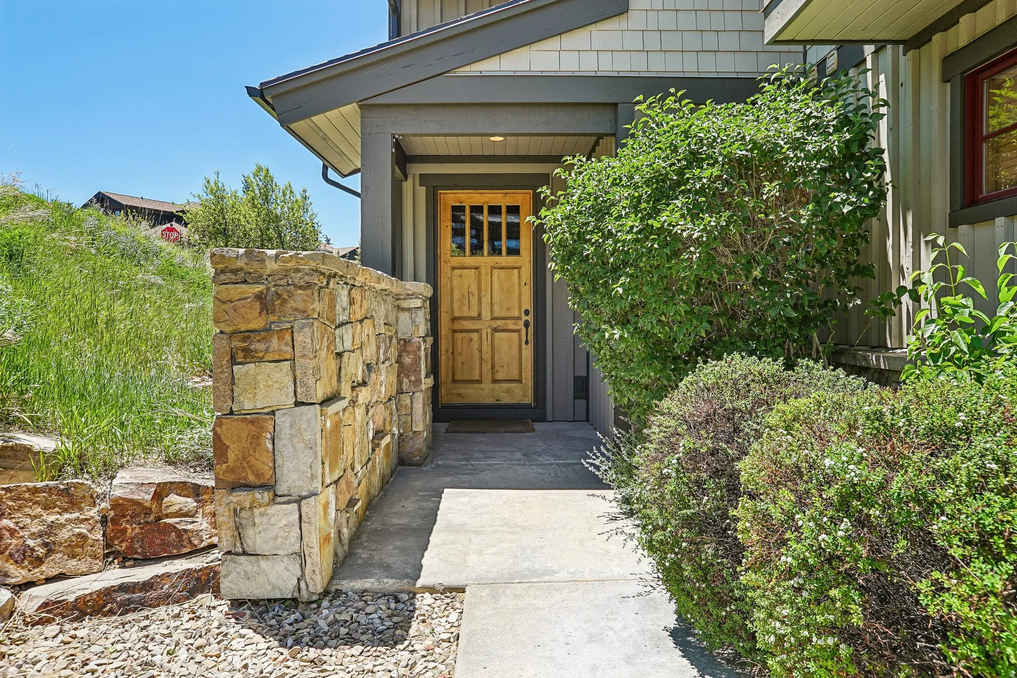 Front entry featuring a natural wood door with glass paneling, an overhead soffit with recessed lighting, and a concrete walkway