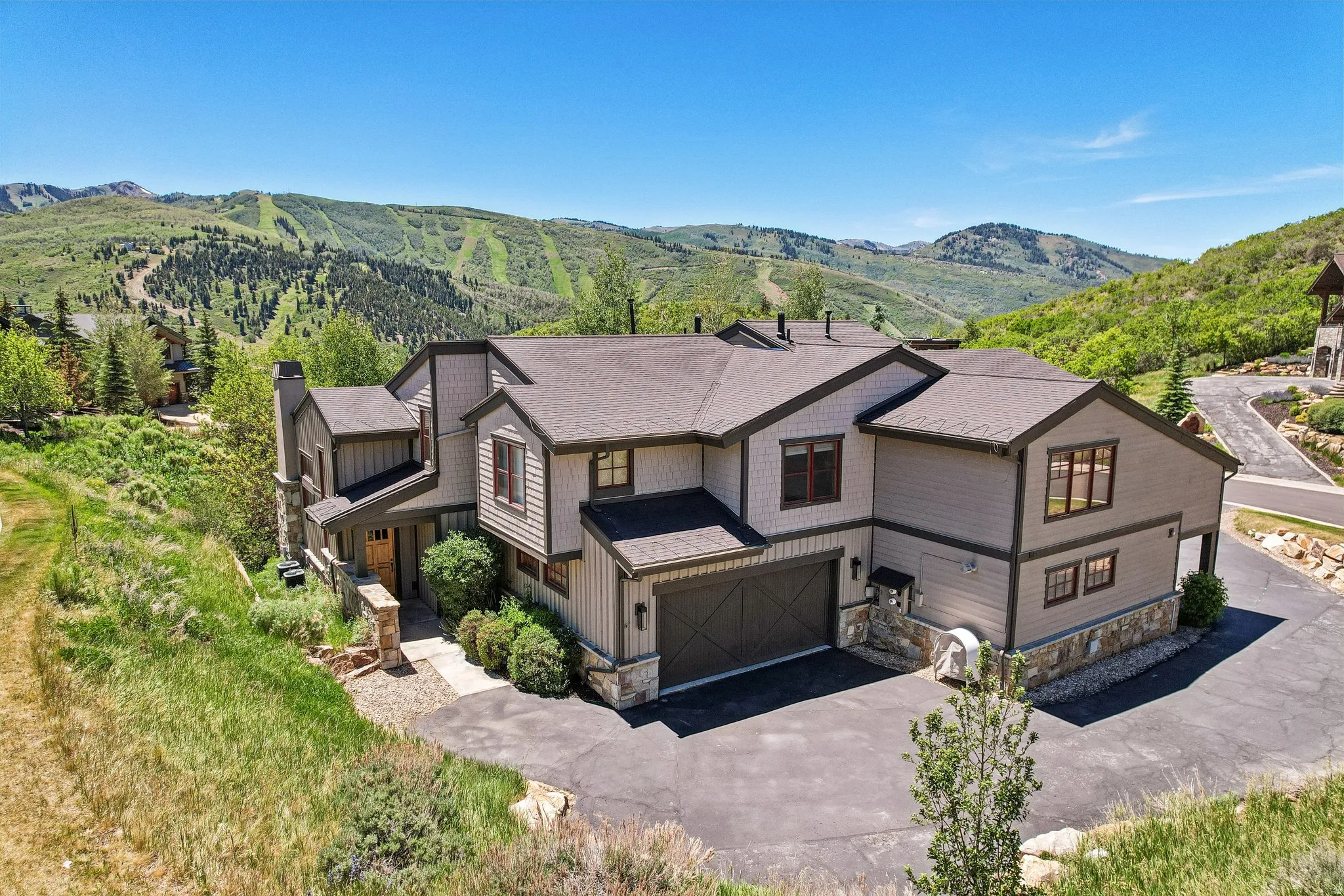 Contemporary residence featuring a multi-tone exterior, stone accents, and a dual-car garage