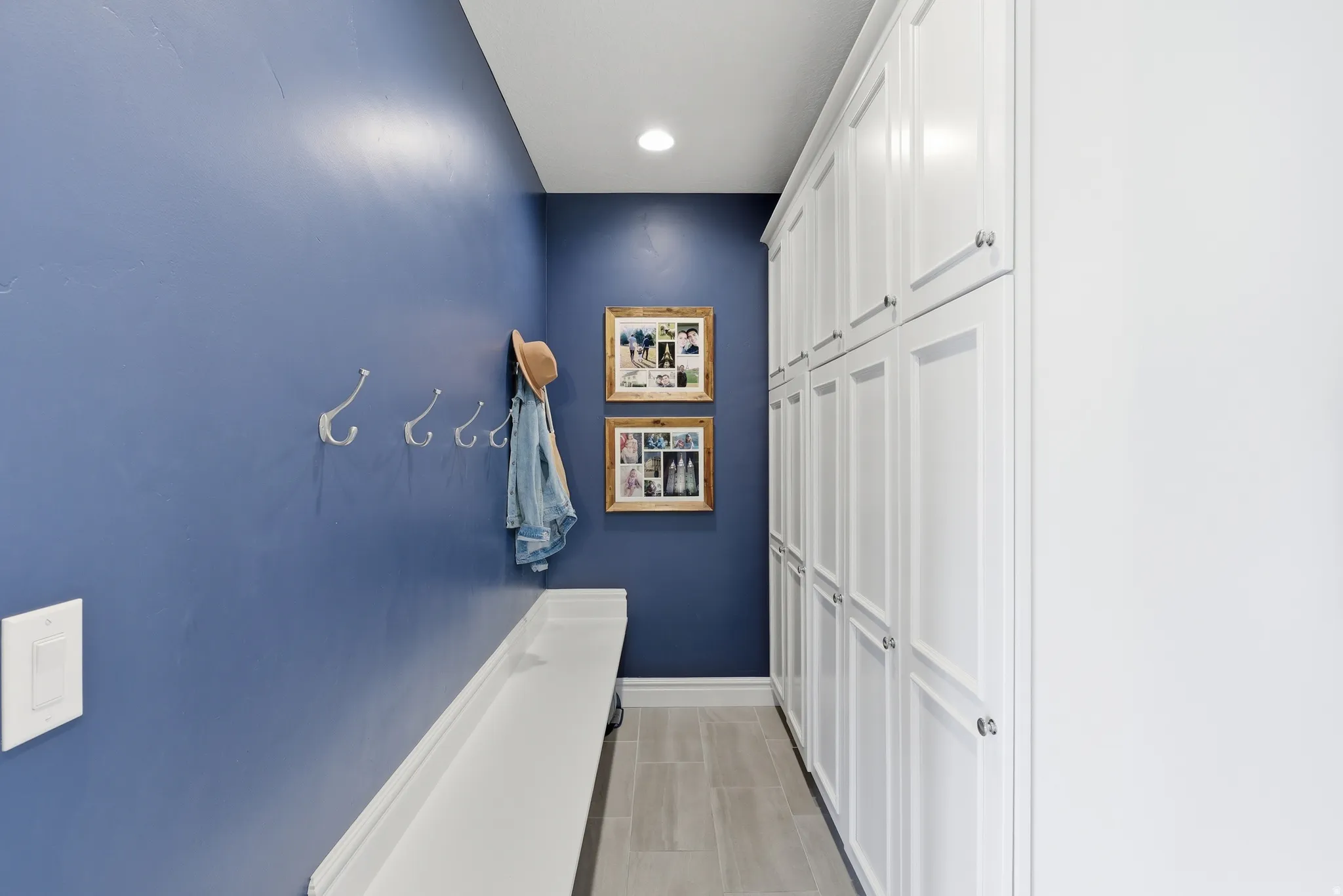 Hallway featuring full-height white cabinetry with silver-tone hardware, recessed lighting, and wood-finish flooring