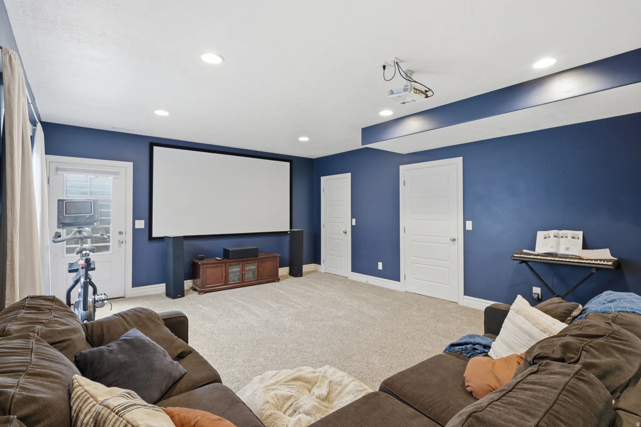 Media room featuring a large projector screen, projector, and recessed lighting