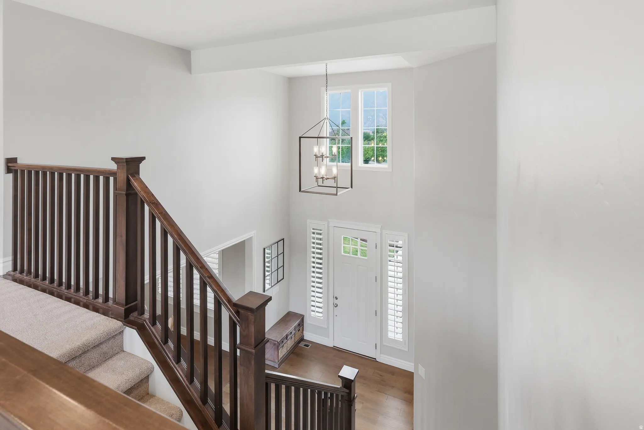 Two-story foyer featuring a contemporary chandelier, high windows, and a white front door with sidelights