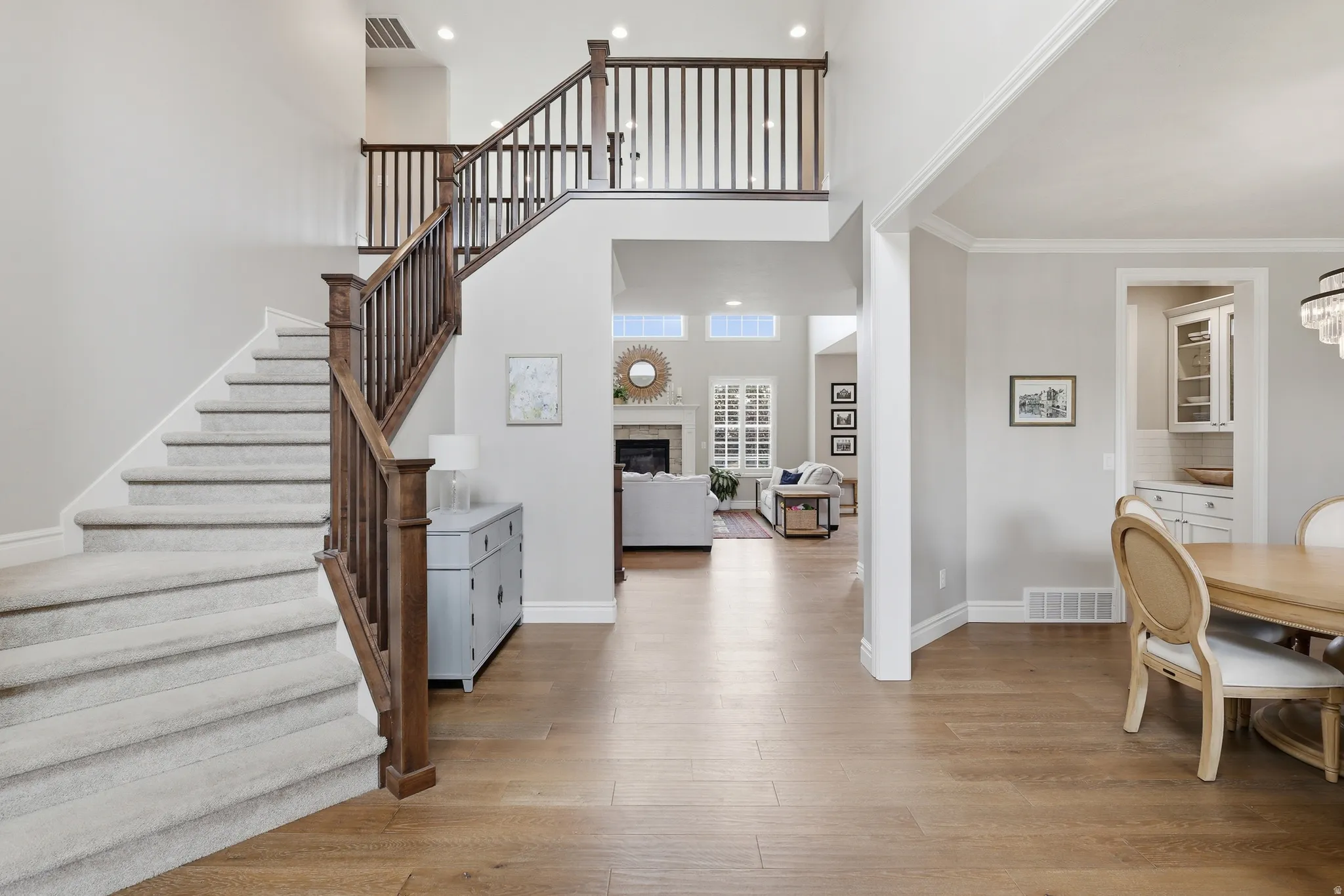 Two-story foyer featuring wood-finish flooring, a grand staircase with carpeted treads and dark wood banister, and a second-story overlook
