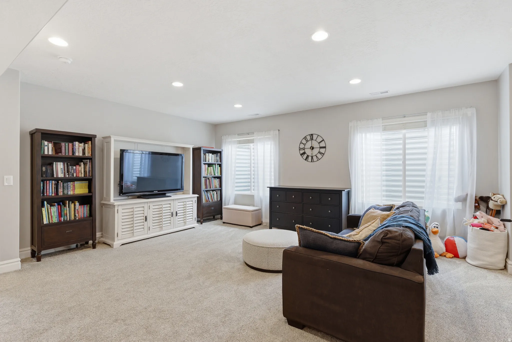 Spacious room featuring light-colored carpet, recessed ceiling lights, and multiple windows with white blinds