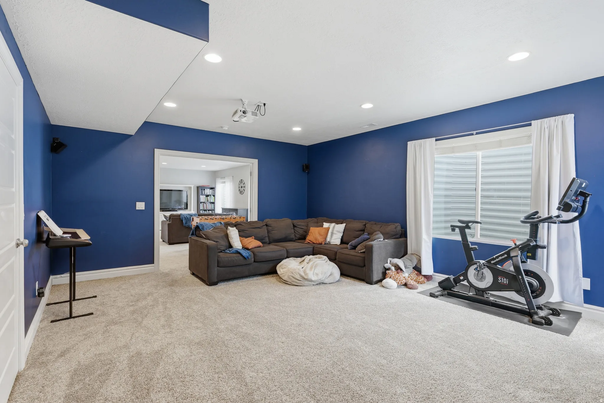 Spacious room featuring plush carpet flooring, recessed lighting, and a white trim baseboard