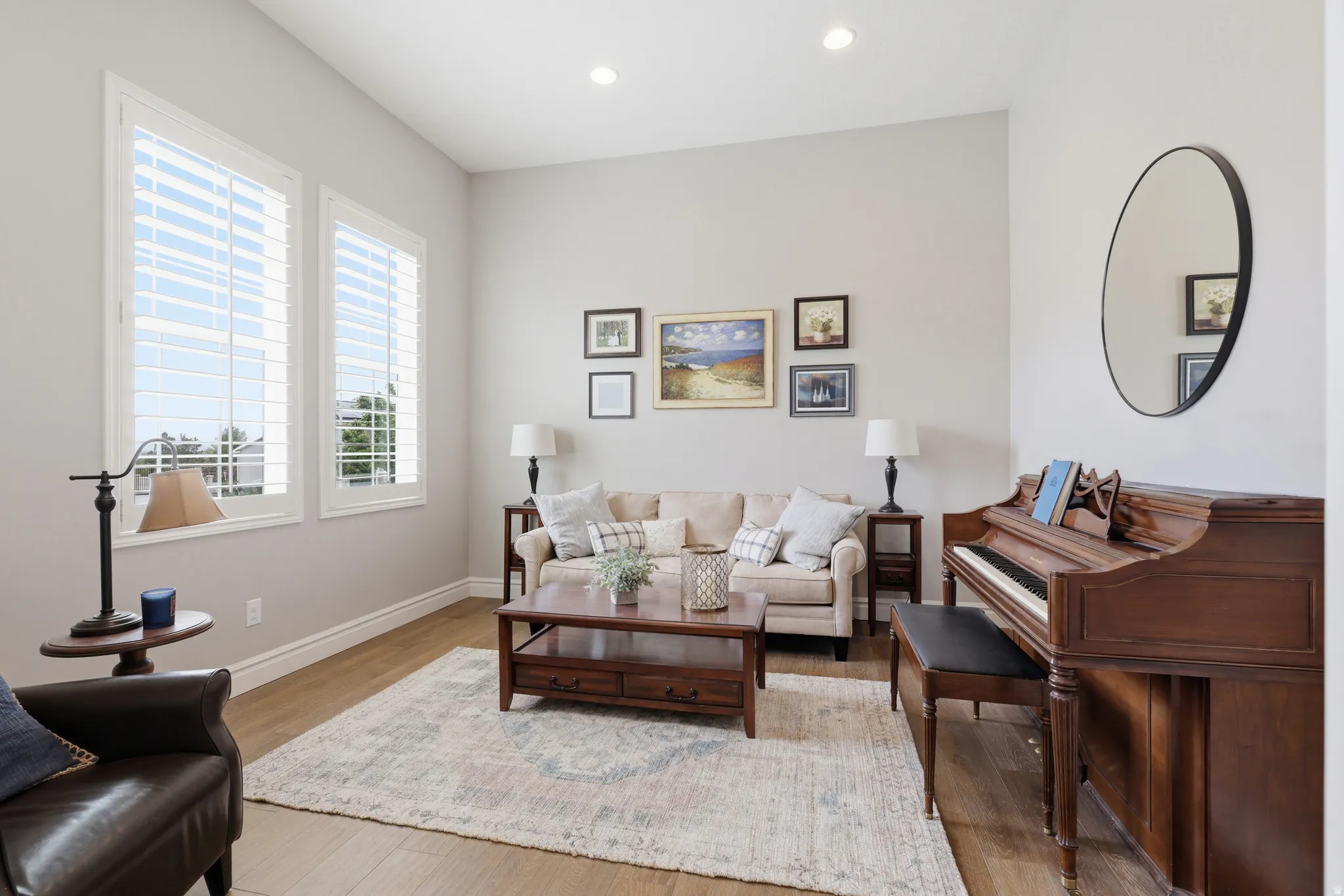 Spacious room featuring wood-finish flooring, tall windows with white plantation shutters, neutral wall tones, and recessed lighting