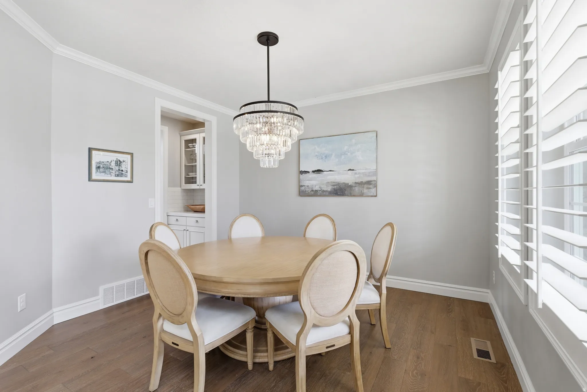 Dining area with wood-finish flooring, crisp white trim, and a tiered crystal chandelier