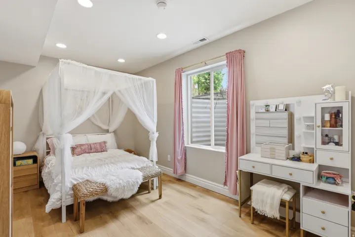 Bedroom featuring wood-finish flooring, recessed lighting, and a window with a white frame