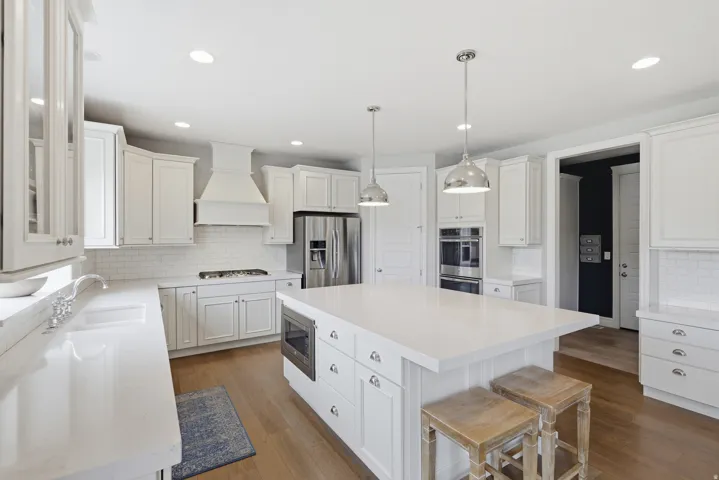 Contemporary kitchen featuring white cabinetry, light wood-finish flooring, and white countertops